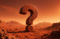 A large rusted metal question mark sculpture stands in a rocky desert landscape under an orange-red sky with a bright sun in the upper right.